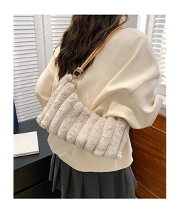 Détail du sac bandoulière en peluche beige clair avec texture rayée et bandoulière en cuir
