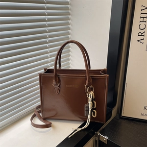 Sac cabas en cuir PU marron avec poignées et bandoulière sur rebord de fenêtre blanc