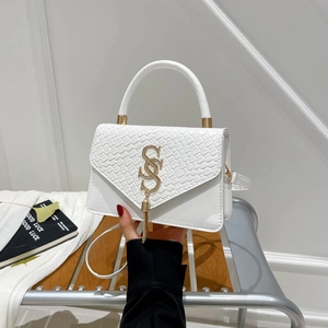 White crossbody handbag with woven texture, metal interlocking clasp, and tassel detail