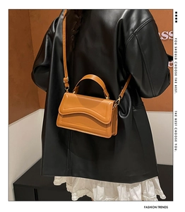 Detail of caramel mini shoulder bag with wavy textured flap and detachable strap