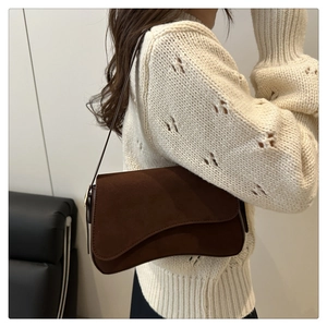 Detail view of a vintage dark brown shoulder bag on a white knitted sweater