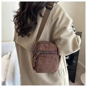 Detail showing brown corduroy texture and adjustable shoulder strap on small crossbody bag