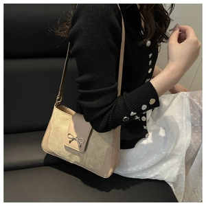 Detail of beige suede crossbody bag featuring an elegant metal bow clasp in French style