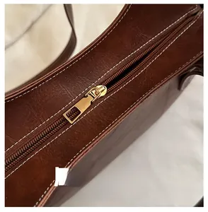 Detailed macro shot of premium brown leather tote with golden zipper and white contrast stitching