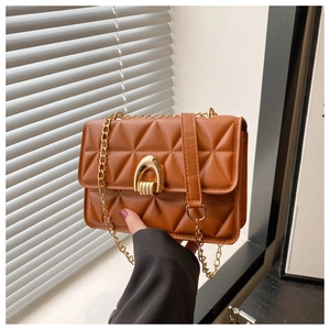 Detail of brown quilted faux leather bag featuring a gold arch-shaped metal lock closure