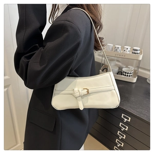 Detailopname van witte lederen baguette tas met decoratieve gouden metalen gesp op de schouderriem