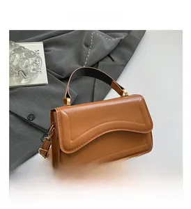 Close-up of brown PU leather shoulder bag with curved stitching and gold hardware detail