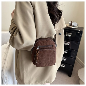 Close-up of brown corduroy crossbody bag with textured zipper and casual retro style