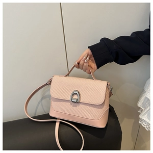 Vue détaillée du sac besace rose avec texture tressée et fermoir métallique en fer à cheval