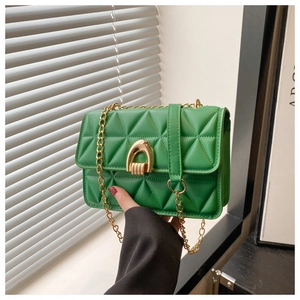 Detail shot of green quilted crossbody bag with gold horseshoe clasp and chain strap