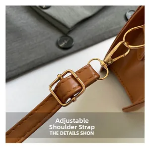 Detail of adjustable brown leather shoulder strap with golden metal lobster clasp and buckle