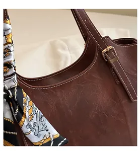 Detail of brown faux leather tote bag with white stitching and decorative silk scarf