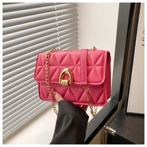 Detail of bright pink quilted crossbody bag with gold horseshoe clasp and chain strap