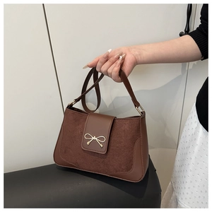 Detail of brown leather and suede crossbody bag featuring a golden bow metal buckle
