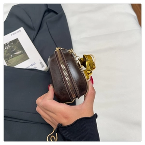 Detail of a dark brown mini bag with golden star zipper pull and textured finish