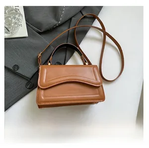Detail view of caramel brown leather handbag with curved stitching and black top handle