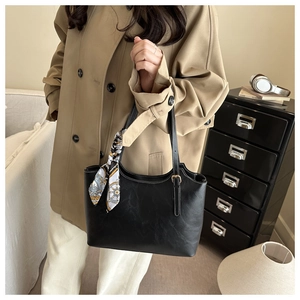 Detail of black leather tote bag with printed silk scarf and metallic buckles