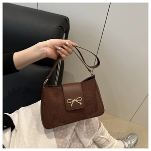 Close-up of brown PU leather shoulder bag featuring suede patchwork and golden bow buckle