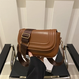 Classic caramel brown saddle crossbody bag with quilted texture and wide nylon strap