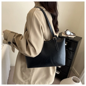 Detail of black leather tote bag with white contrast stitching and adjustable gold buckle