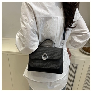 Vue détaillée du sac besace noir tissé avec boucle en U argentée et bandoulière fine