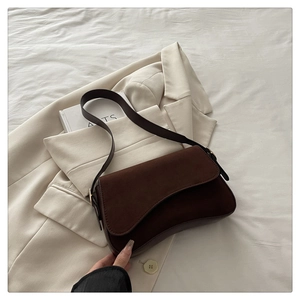 Detail of dark brown suede underarm bag on blazer highlighting retro matte leather texture