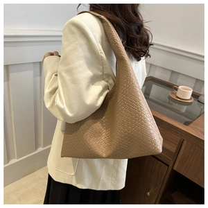 Détail du sac hobo tissé marron clair de grande capacité avec une texture fine sur un modèle