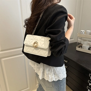 White quilted shoulder bag with gold chain strap and horseshoe buckle on model