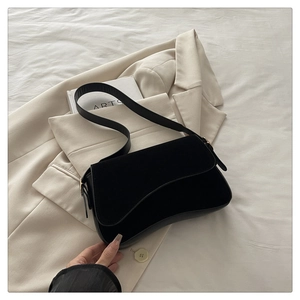 Detail of black matte suede shoulder bag with elegant curved flap and metal buckle
