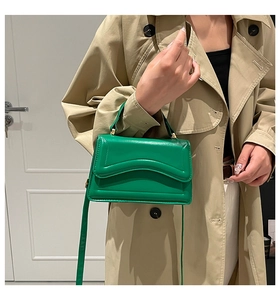 Close-up of emerald green leather crossbody bag with distinctive wavy textured flap detail