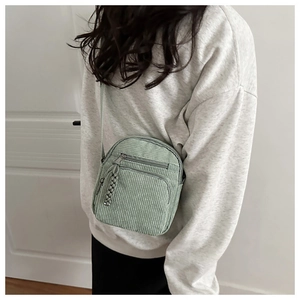 Detailed shot of mint green corduroy crossbody bag with woven zipper pullers and two pockets
