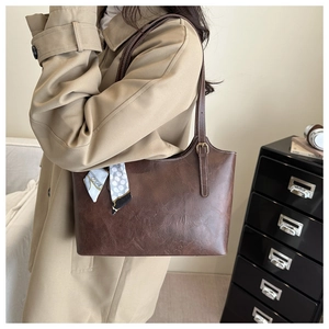 Close-up of brown tote bag with premium leather texture and stylish polka dot scarf detail