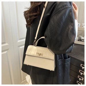 Close-up of minimalist beige PU leather crossbody bag with elegant gold swivel lock