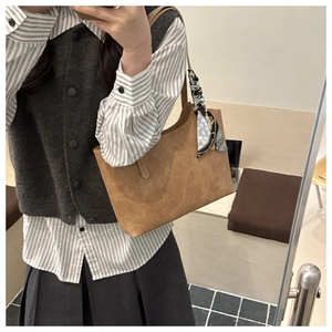 Detail of brown tote bag with vintage leather texture and decorative polka dot scarf