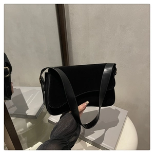 Close-up of black velvet shoulder bag with adjustable gold buckle and leather strap