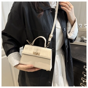 Detail of a creamy beige crossbody bag with gold twist lock and matte leather texture