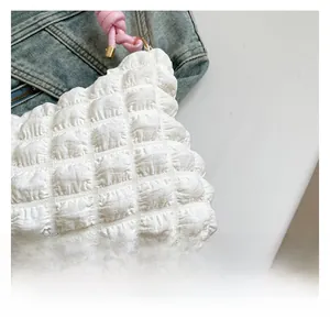 Detailed close-up of white bubble texture fabric with pink knotted handle and metal hardware