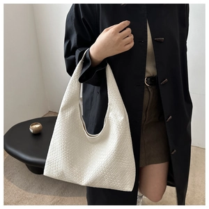 Gros plan sur le sac hobo beige en cuir tressé montrant sa texture et son porté épaule
