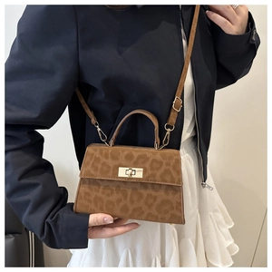Detail of leopard print crossbody bag with gold twist lock and adjustable strap on model