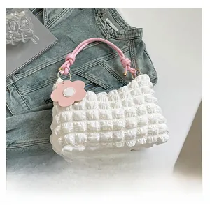 Detailed shot of bubble texture fabric and pink woven handle on a white cylinder bag