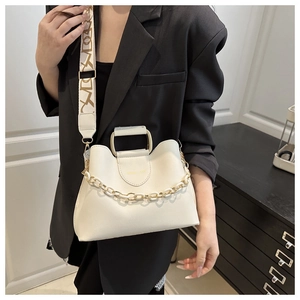 Detail of white bucket bag with decorative thick chain and Amelie & Joy logo on black blazer