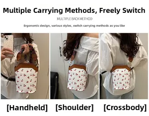 Borsa a secchiello crema con ciliegie mostrata a mano, a spalla e a tracolla sportiva