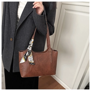 Brown tote bag detail with contrast stitching and decorative printed silk scarf on handle