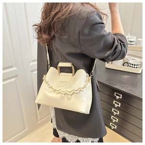 Detail of cream bucket bag with gold handle and chunky white chain strap on model