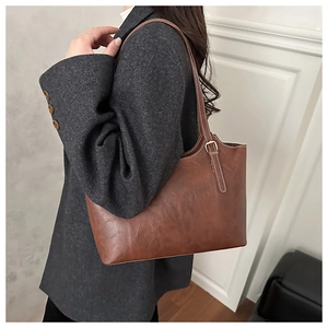 Detailed view of caramel brown tote bag with contrast stitching and golden hardware