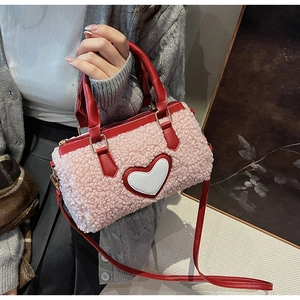 Detail of pink faux shearling cylinder bag with red leather straps and heart patch