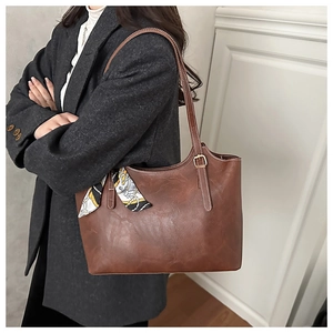 Close-up of vintage brown tote bag with decorative floral scarf and gold hardware detail