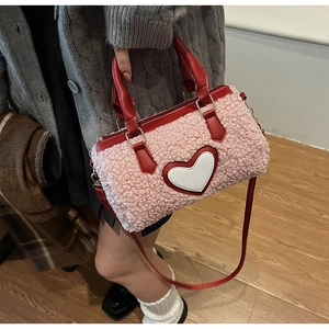 Detailed view of a pink plush crossbody bag with heart motif and red leather straps