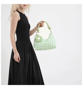 Detailed shot of mint green bubble fabric bag with floral charm and gold ring handles