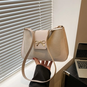 Elegant beige solid color shoulder bag with a gold bow detail and textured leather finish